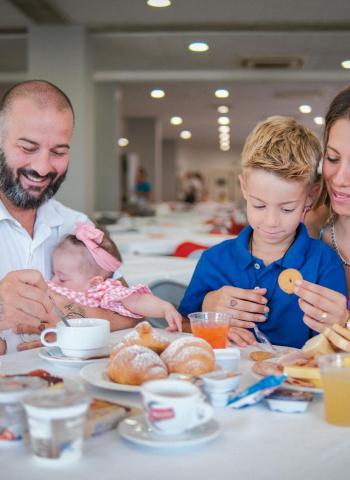 Famiglia felice fa colazione insieme in un ristorante luminoso.